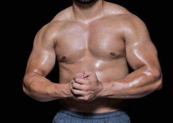 Mid section of a shirtless muscular man against black background